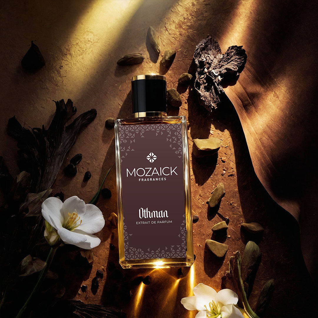 OTHMAN Extrait de Parfum 50 ml by MOZAICK – bottle on a dark surface with white flowers and pieces of wood